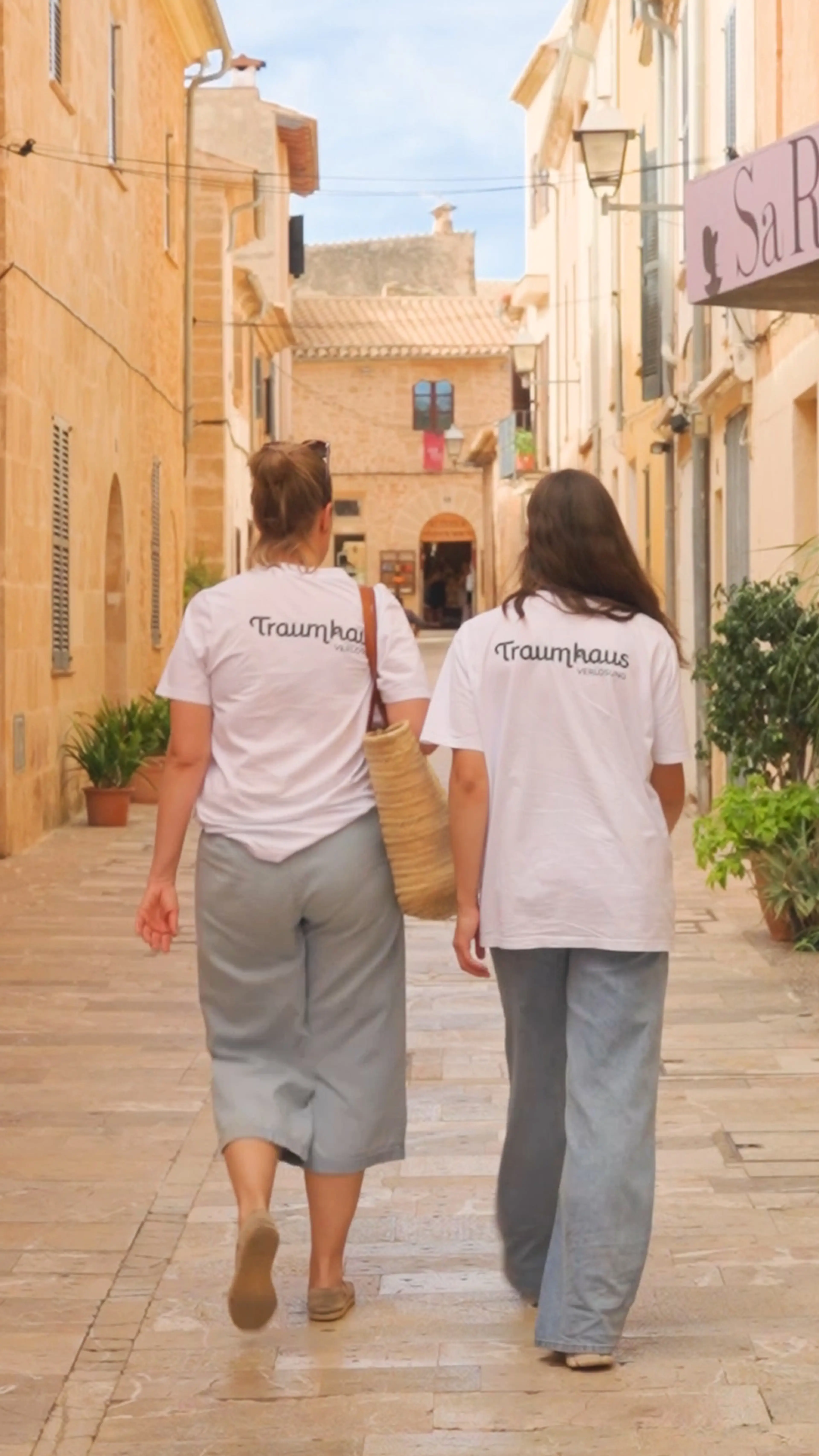 Aufnahme von hinten: Anna und Fredi von der Traumhausverlosung schlendern durch die Gassen einer kleinen Stadt auf Mallorca