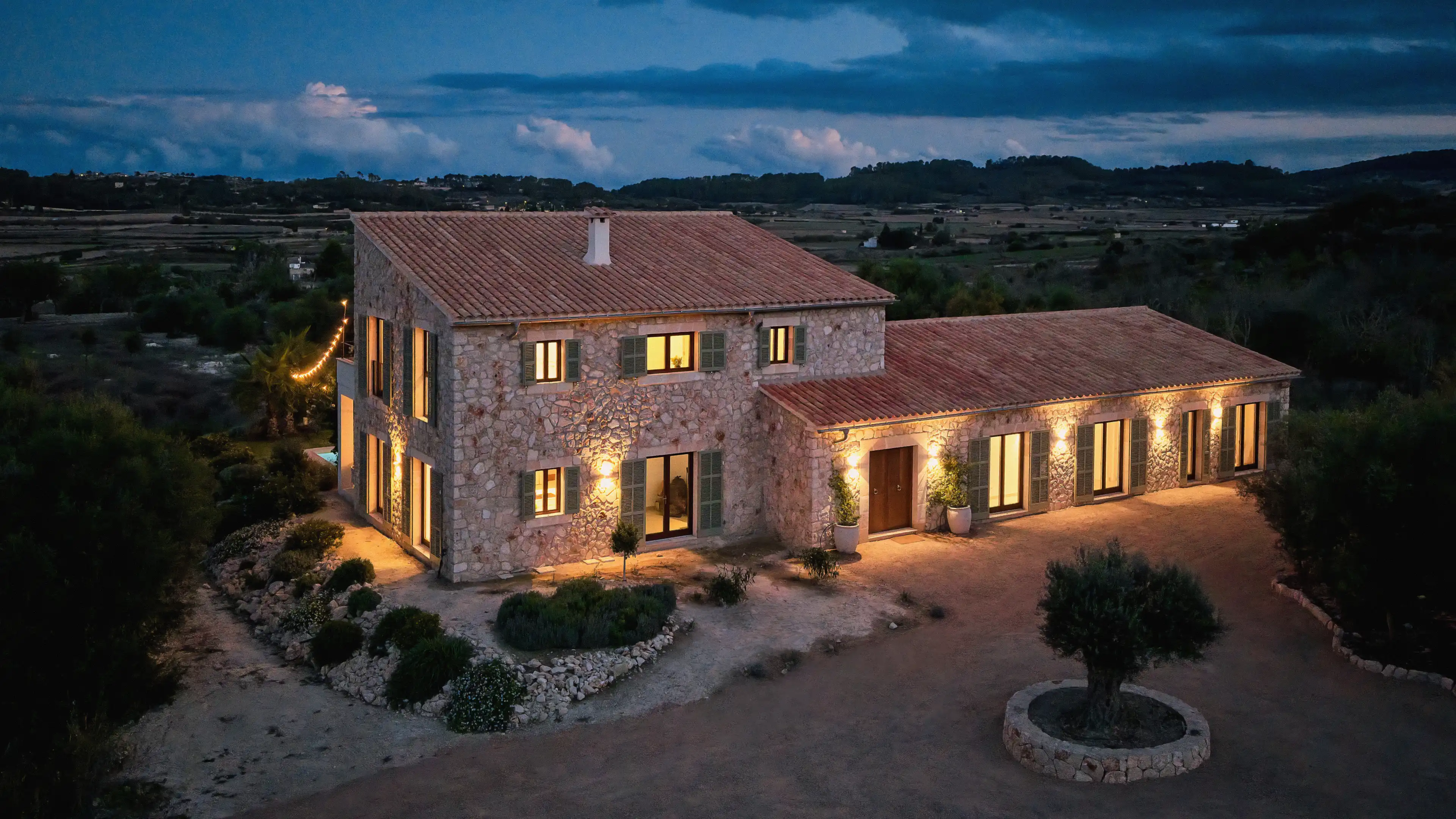 Außenansicht des Traumhauses auf Mallorca in der Abenddämmerung  mit Blick auf den beleuchteten Eingangsbereich und die große Auffahrt