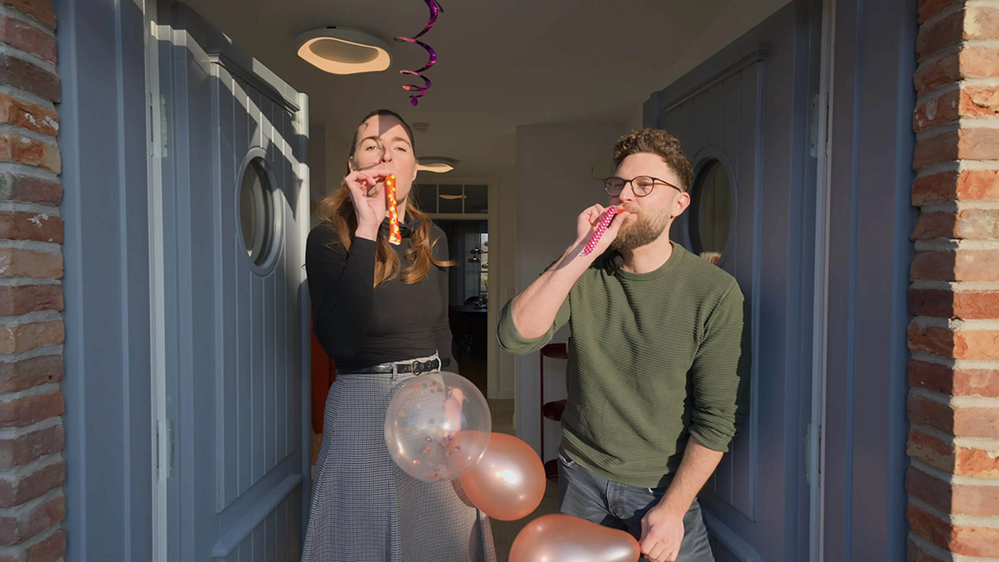 Pia und Jan von der Traumhausverlosung stehen im mit Luftballons geschmückten Eingangsbereich des Traumhaus auf Föhr