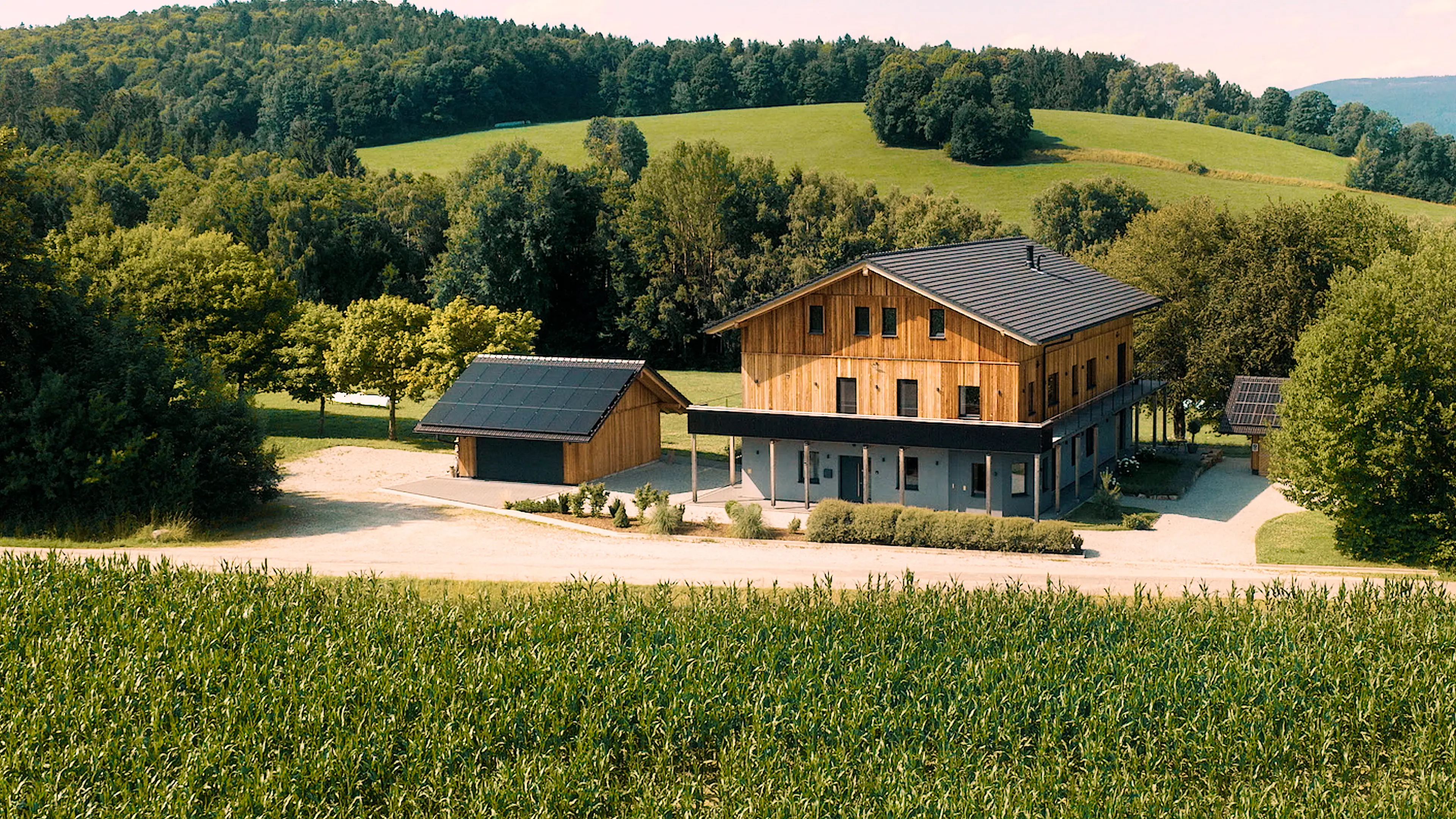 Das Traumhaus im Bayersichen Wald mit grünen Hügeln und Wald im Hintergrund