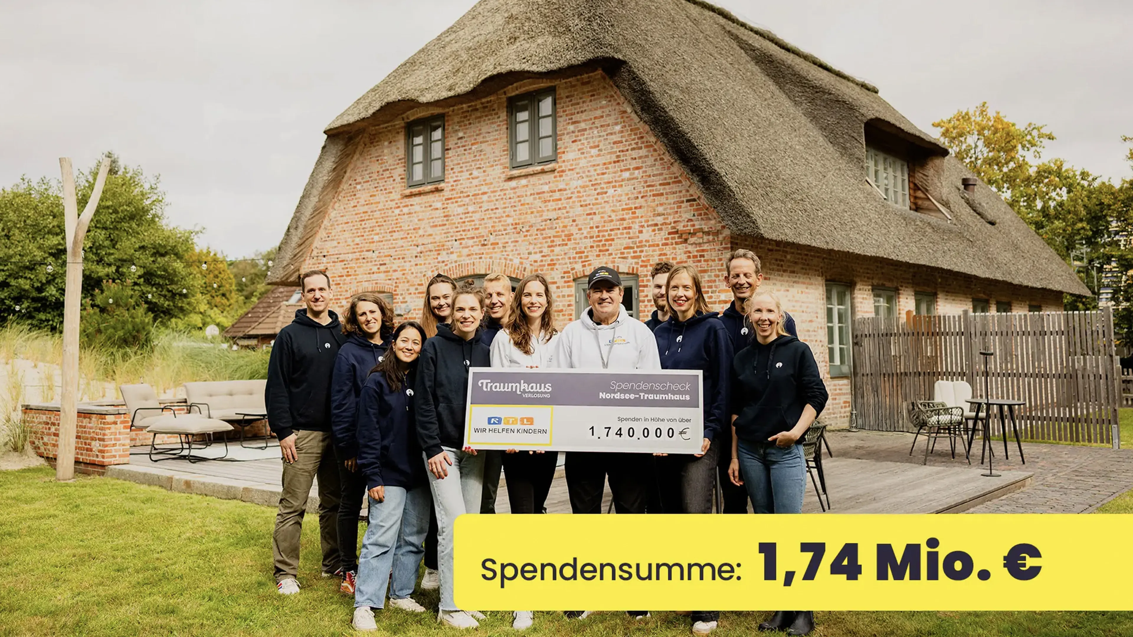 Das Team er Traumhausverlosung und RTL - Wir helfen Kindern stehen mit dem Spendencheck im Garten des Nordseetraumhauses