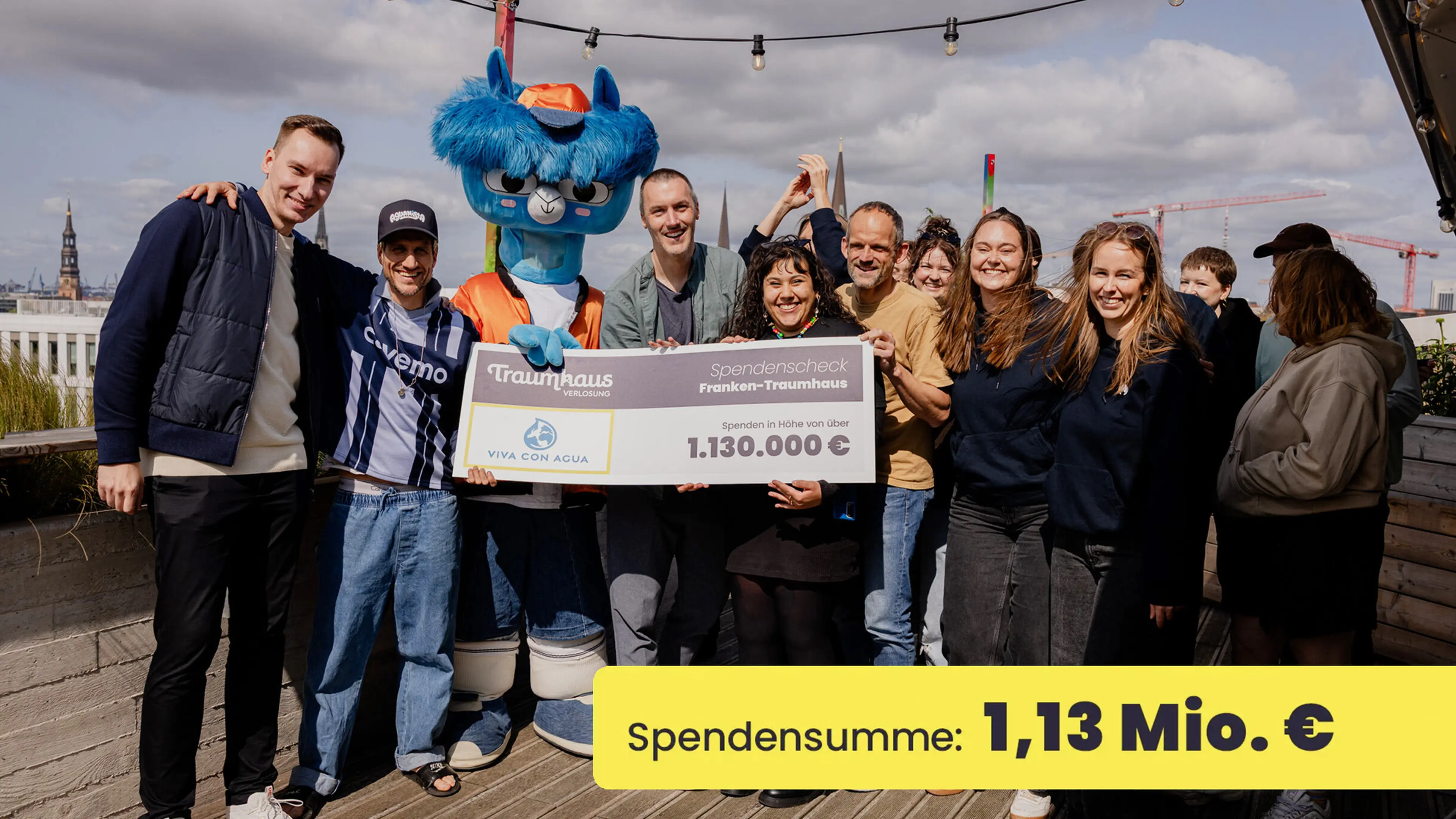 Das Team der Traumhausverlosung und das Team von Viva con Agua mit dem Spendencheck auf der Dachterrasse der Villa Viva
