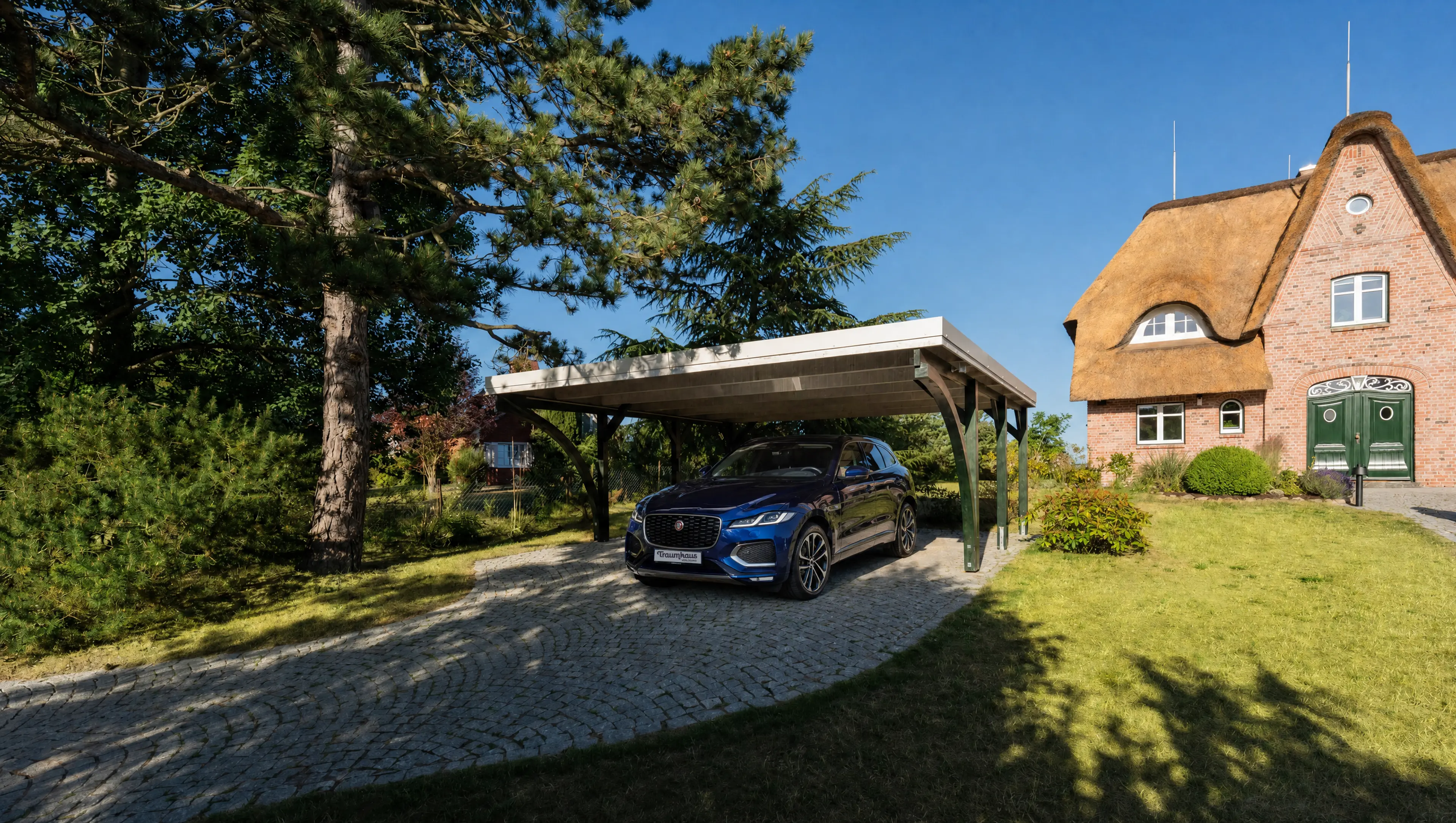Blauer Jaguar-F-Pace unter dem Carport vor dem Traumhaus mit Ostseeblick