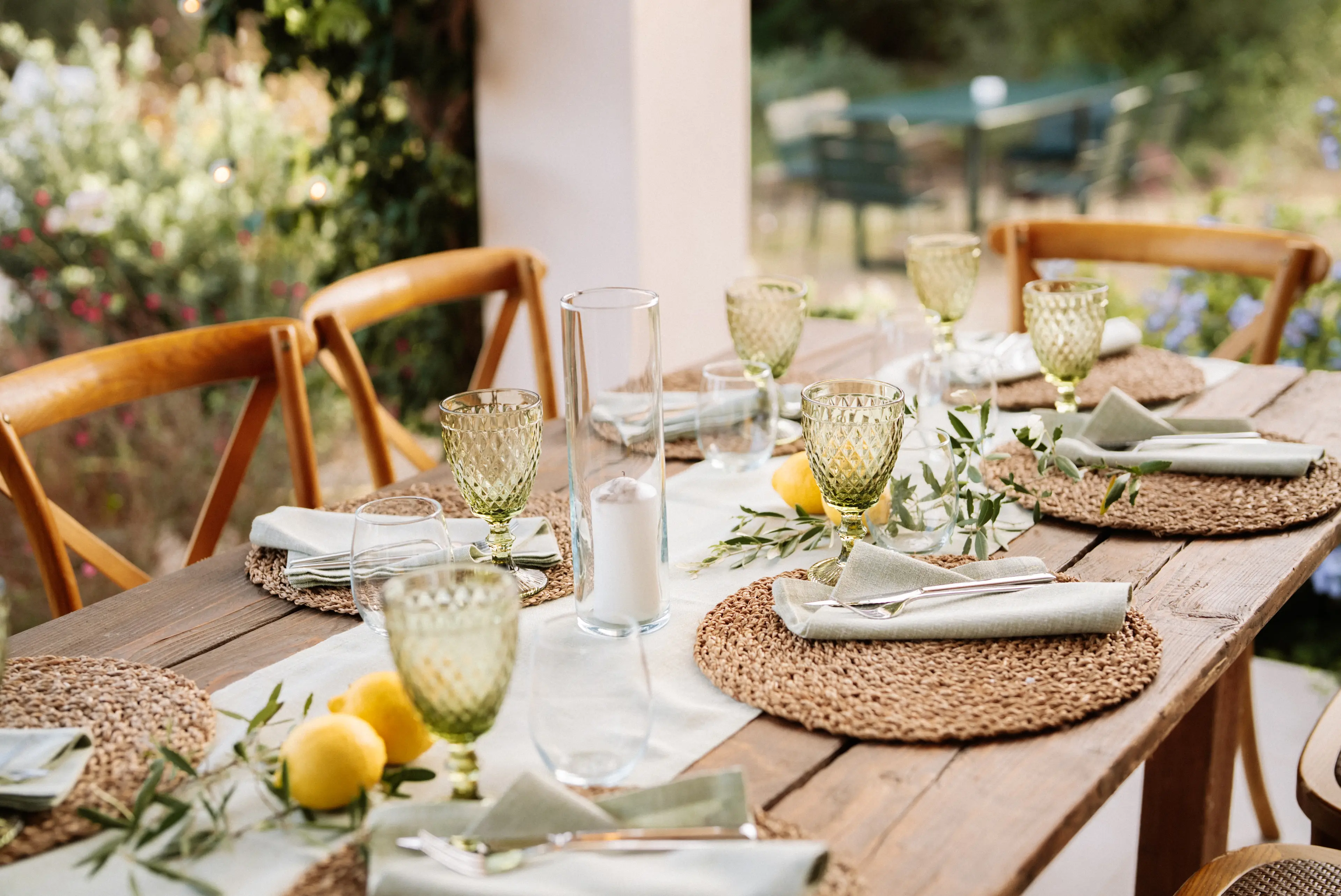 Nahaufnahme eines sommerlich gedeckten großen Holztisch im Freien