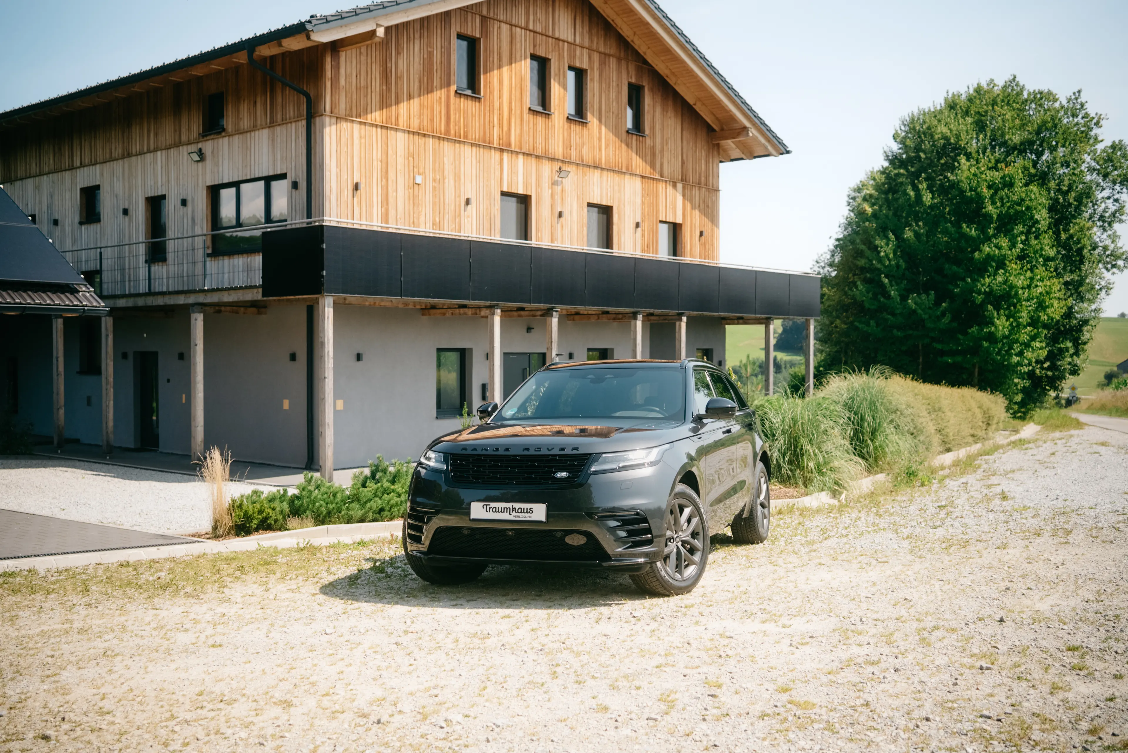 Ein schwarzer Range Rover Velar Plug_in Hybrid geparkt vor der Einfahrt des Traumhauses im Bayerischen Wald