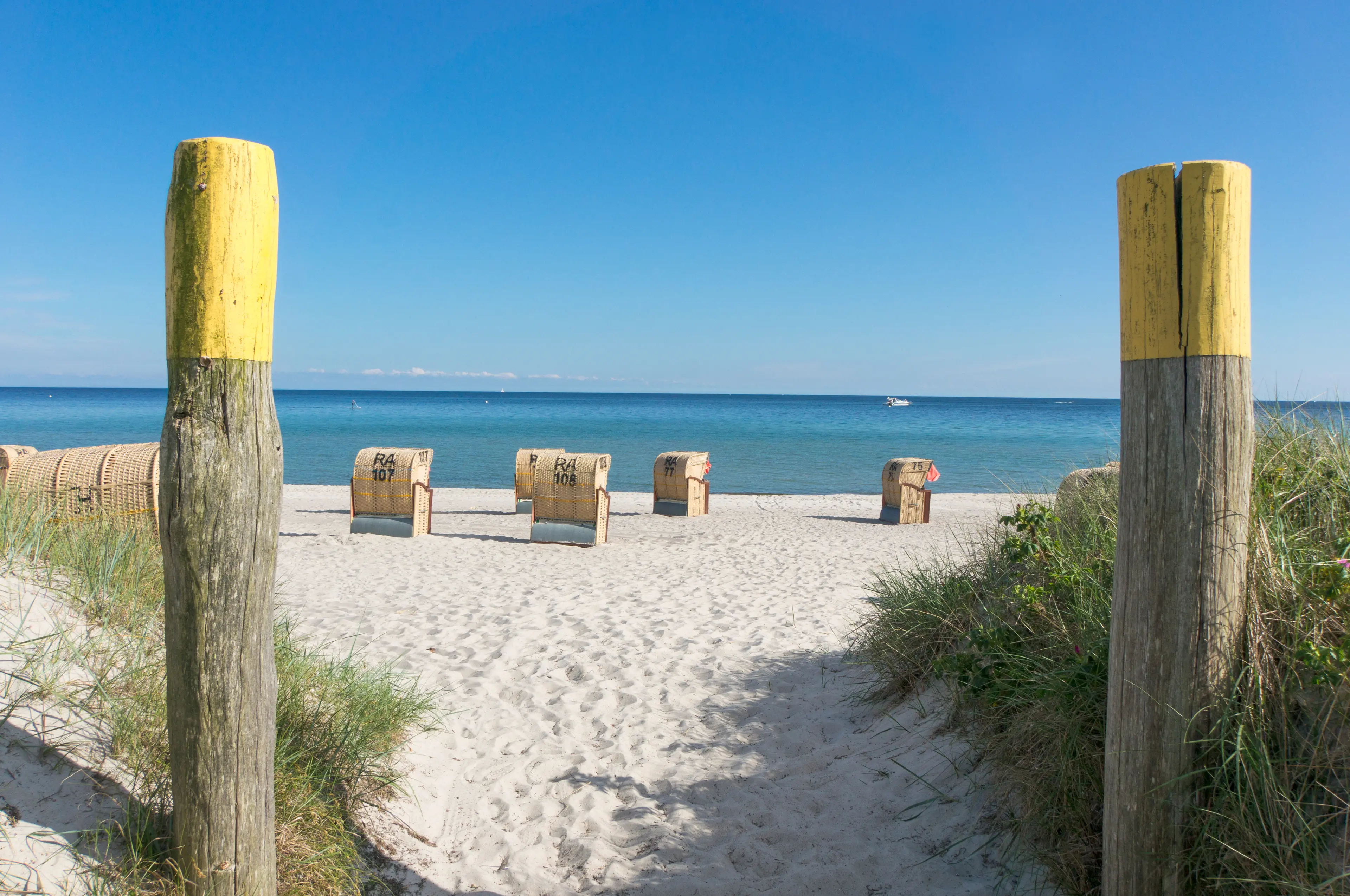 Strandzugang mit Strandkörben am weißen Sandstrand an der Ostsee.