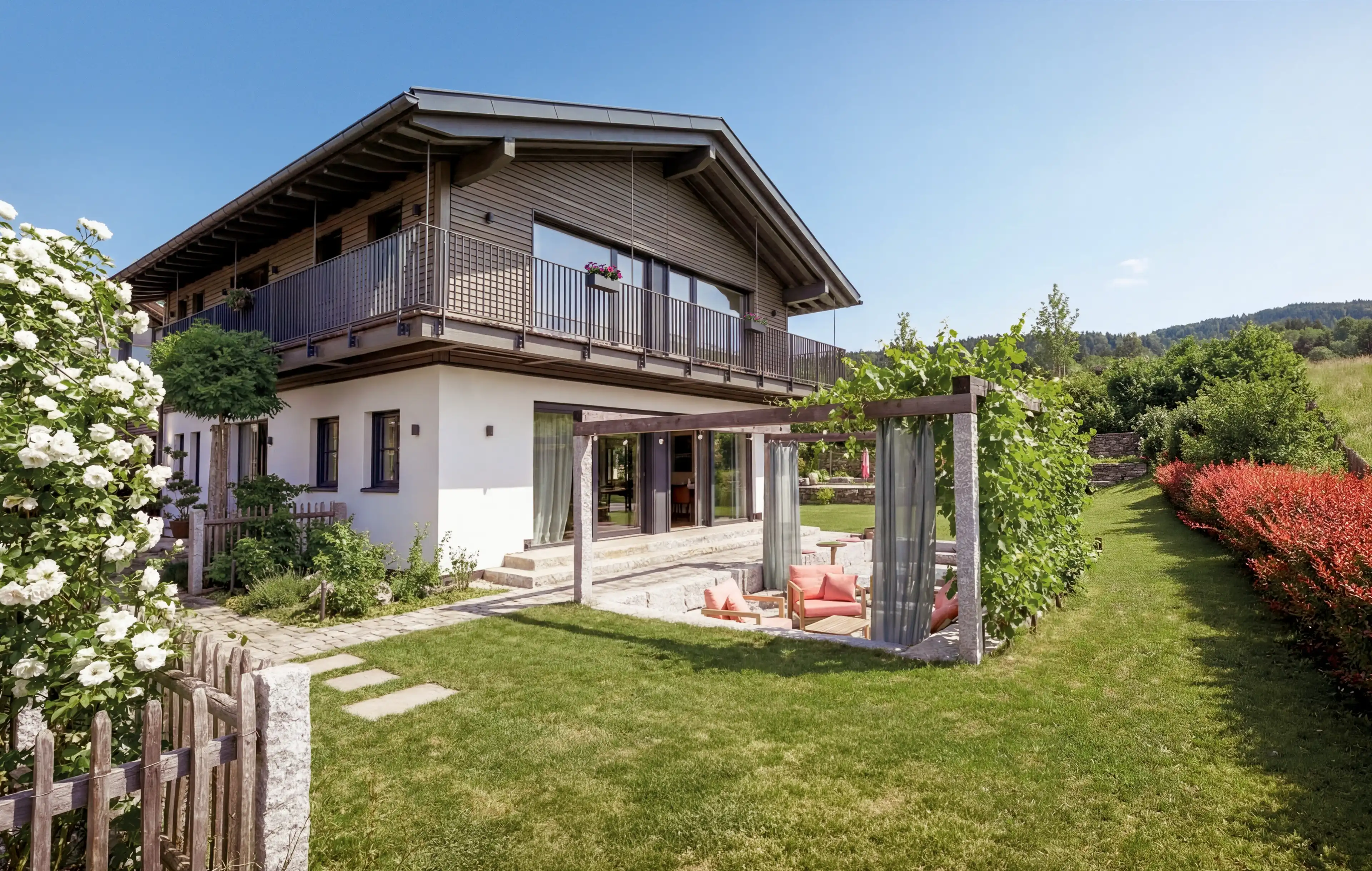 Blick auf das Traumhaus am Chiemsee und den Garten mit Feuerstelle und Sitzgelegenheiten