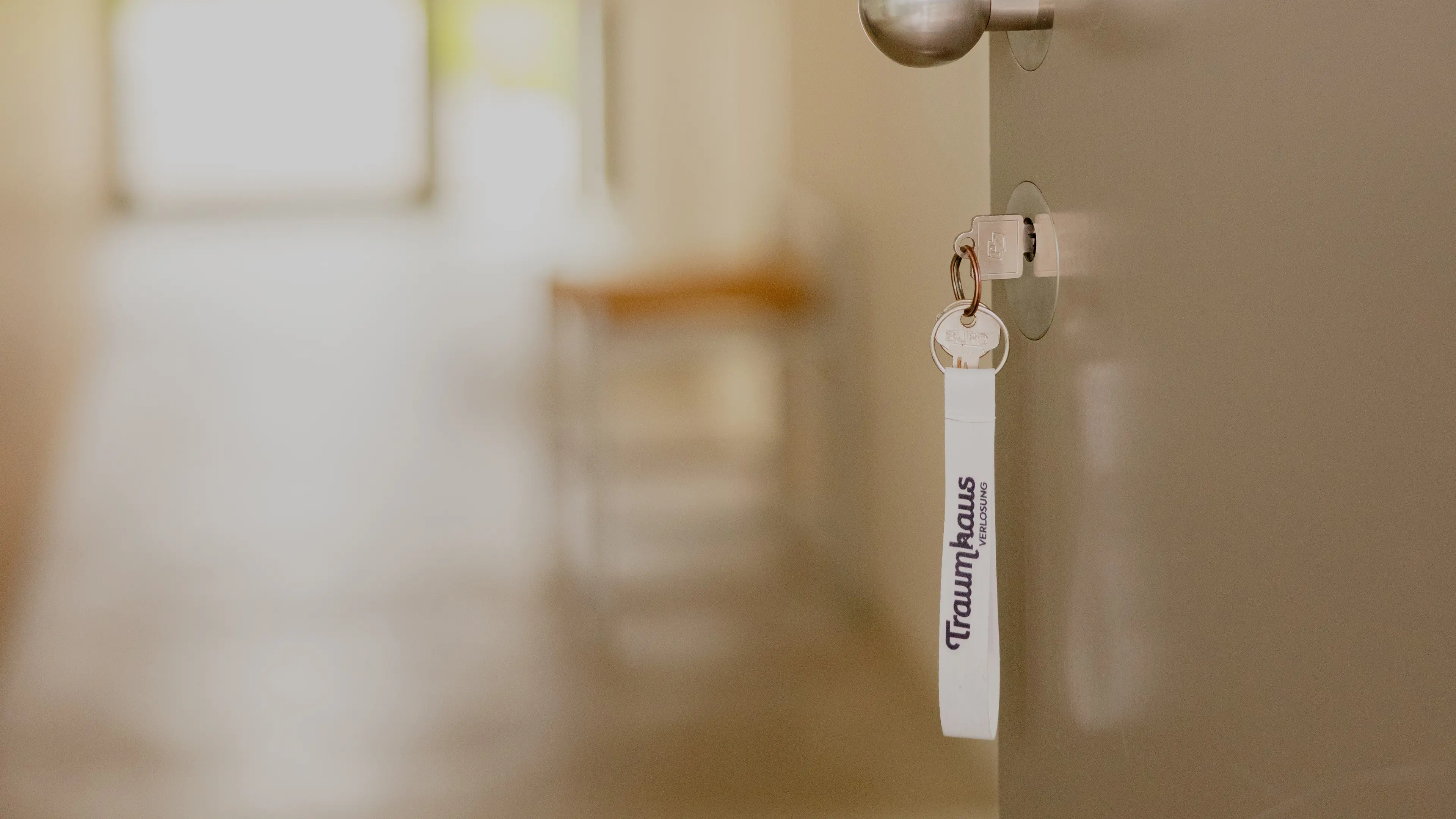 Offene Eingangstür mit einem Schlüssel an dem ein Traumhausverlosungs-Schlüsselband hängt