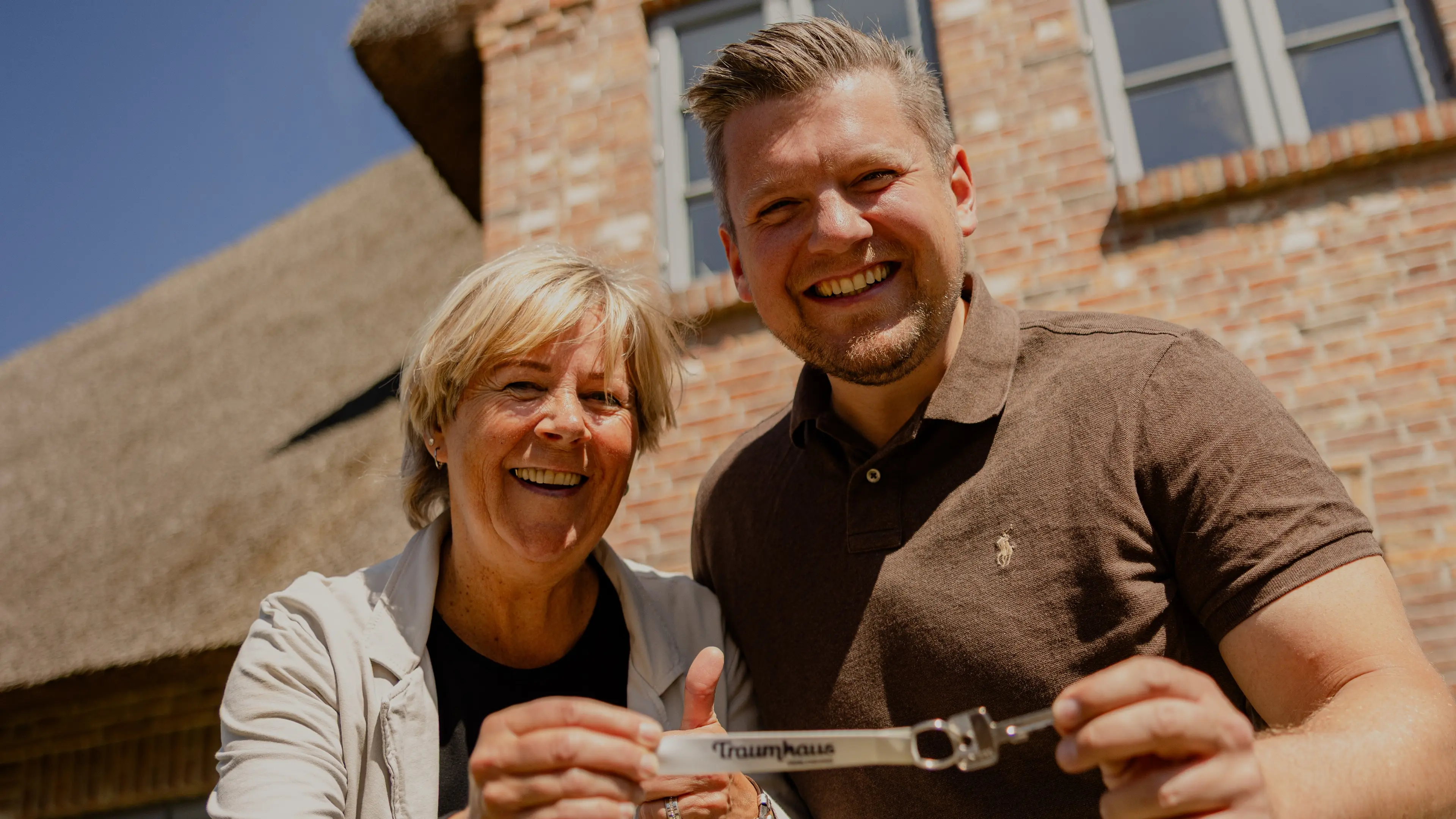 Birgit und ihr Sohn halten voller Freude den Schlüssel vom Traumhaus auf Föhr in die Kamera