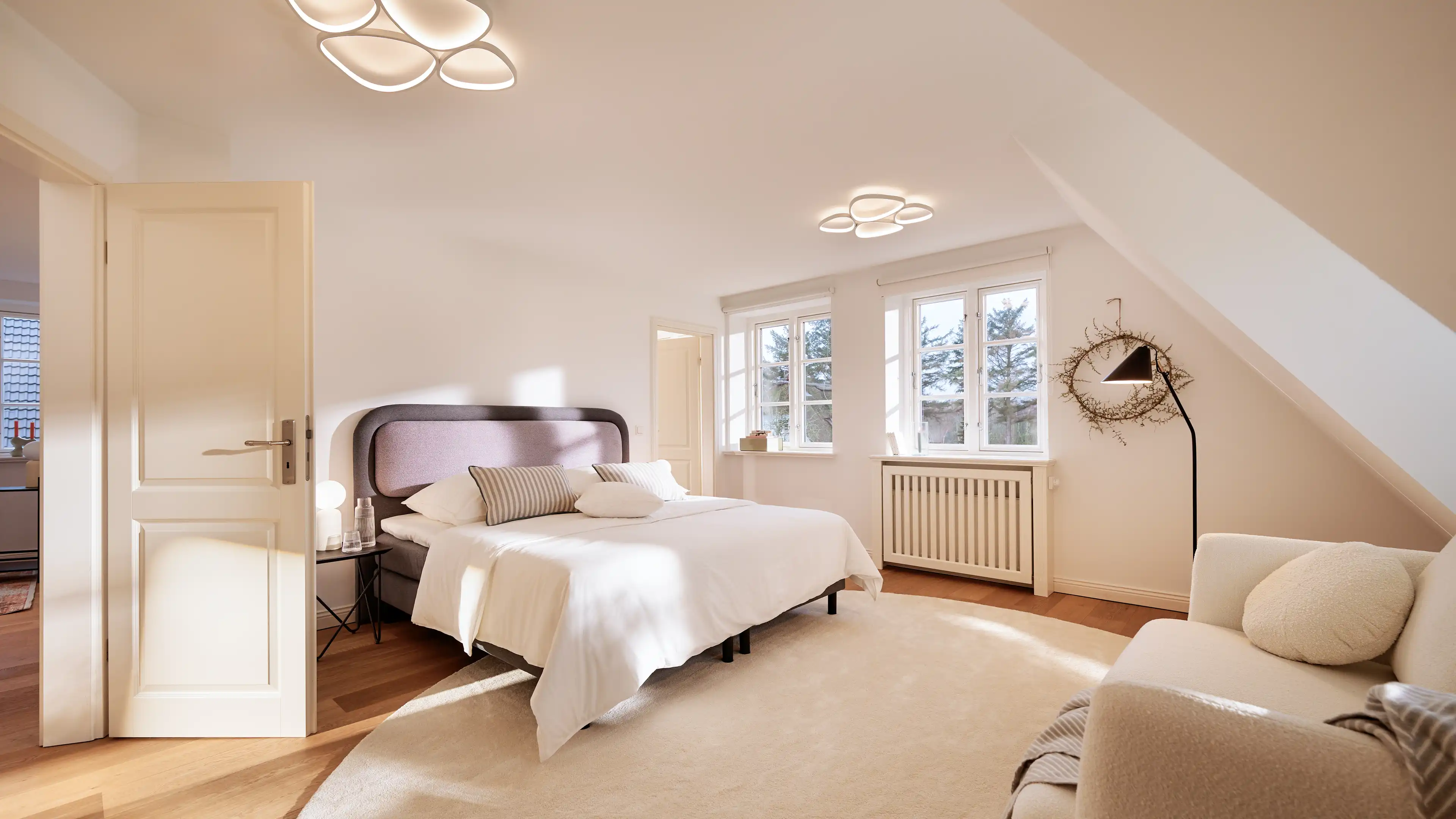 Helles Schlafzimmer im Traumhaus auf Föhr mit großem Bett, Dachschräge und stilvoller Einrichtung.