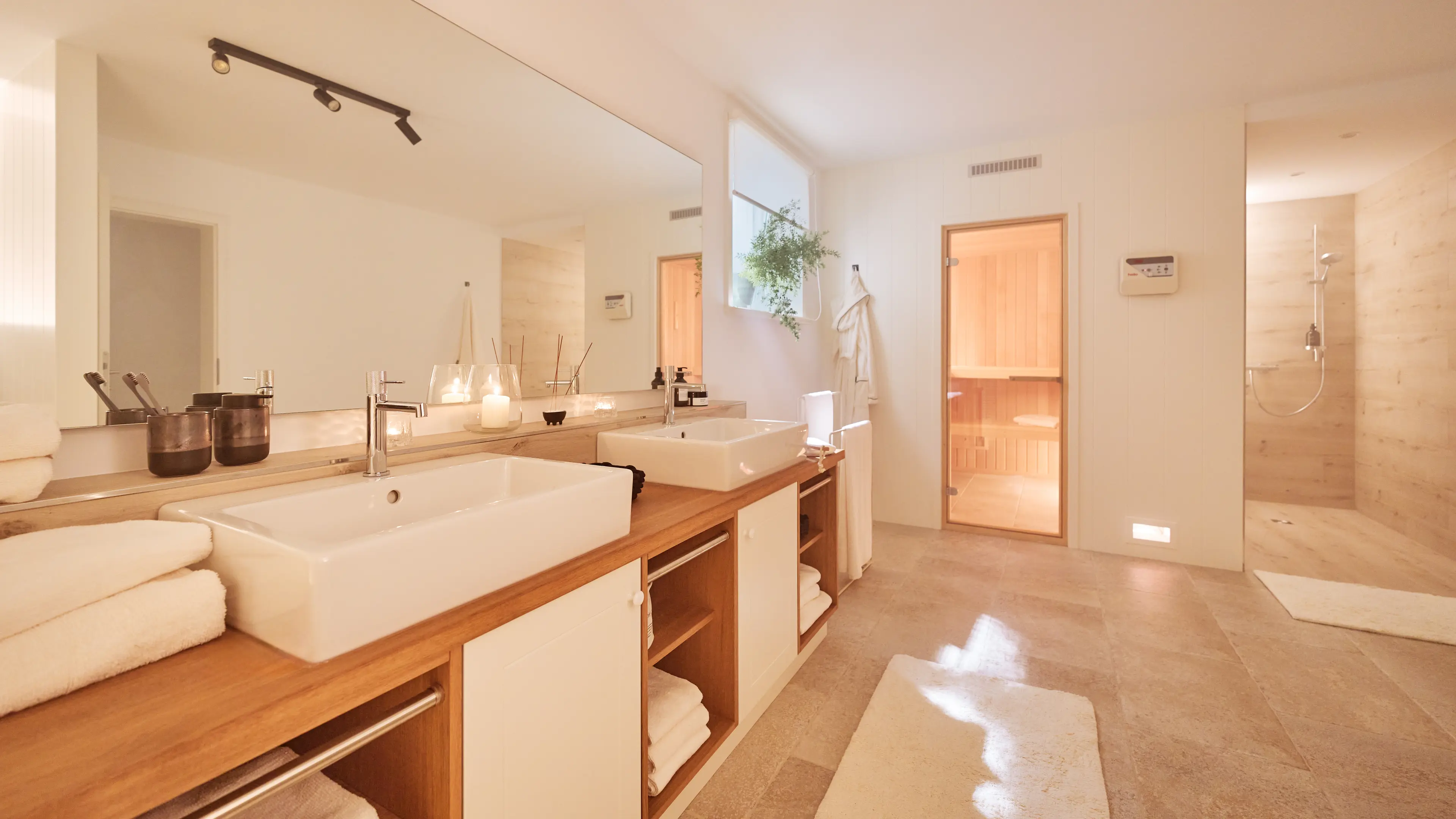 Hochwertiges Wellnessbad im Traumhaus auf Föhr mit Doppelwaschbecken, Sauna und moderner Dusche.