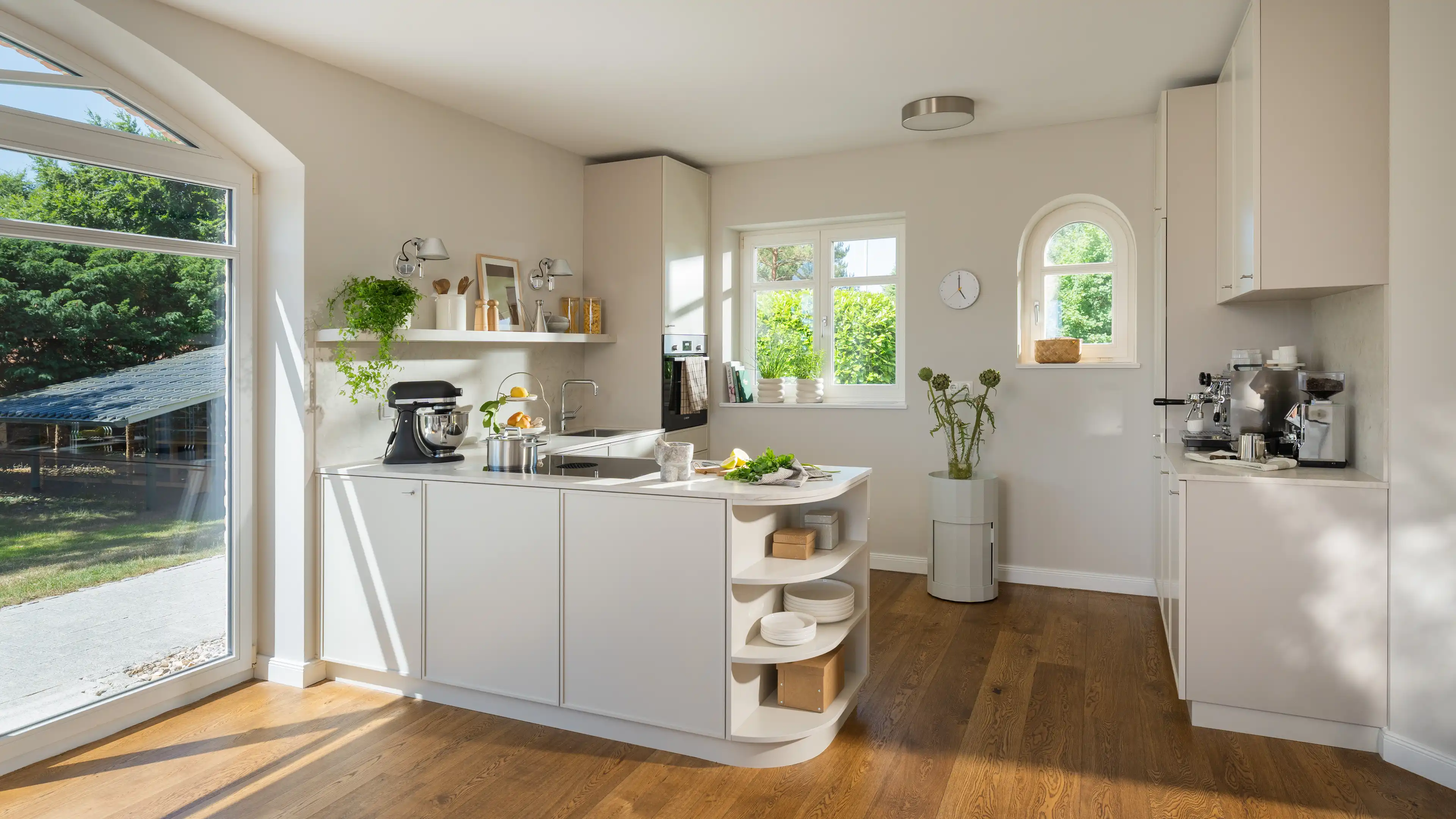 Helle, cremefarbene Küche mit geschwungener Kücheninsel, freistehendem Regal, Küchenmaschine und einer eigenen Kaffeestation.
