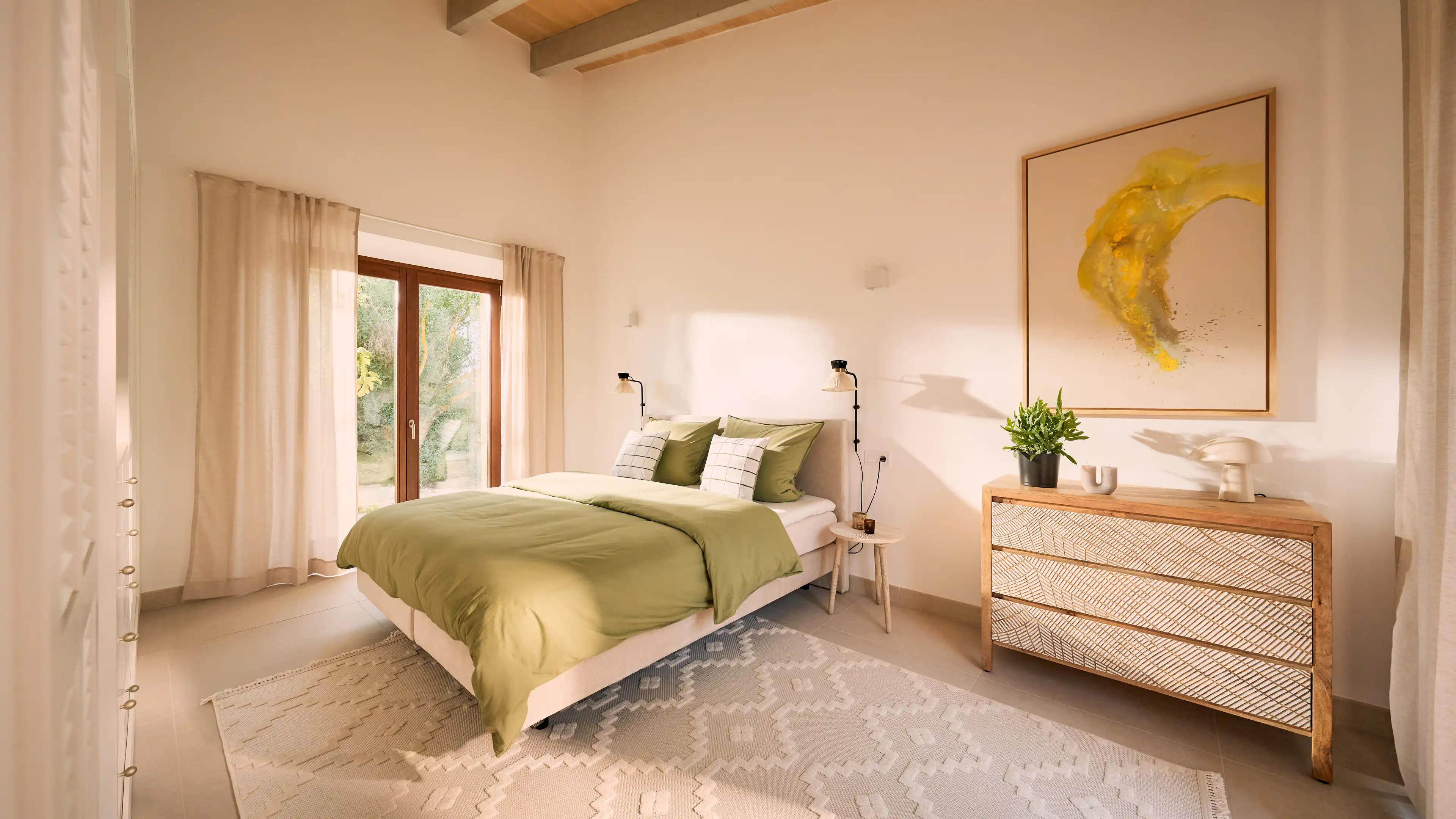 Helles Schlafzimmer im Traumhaus auf Mallorca mit grüner Bettwäsche, modernen Nachttischen und großem Fenster mit Blick ins Grüne.