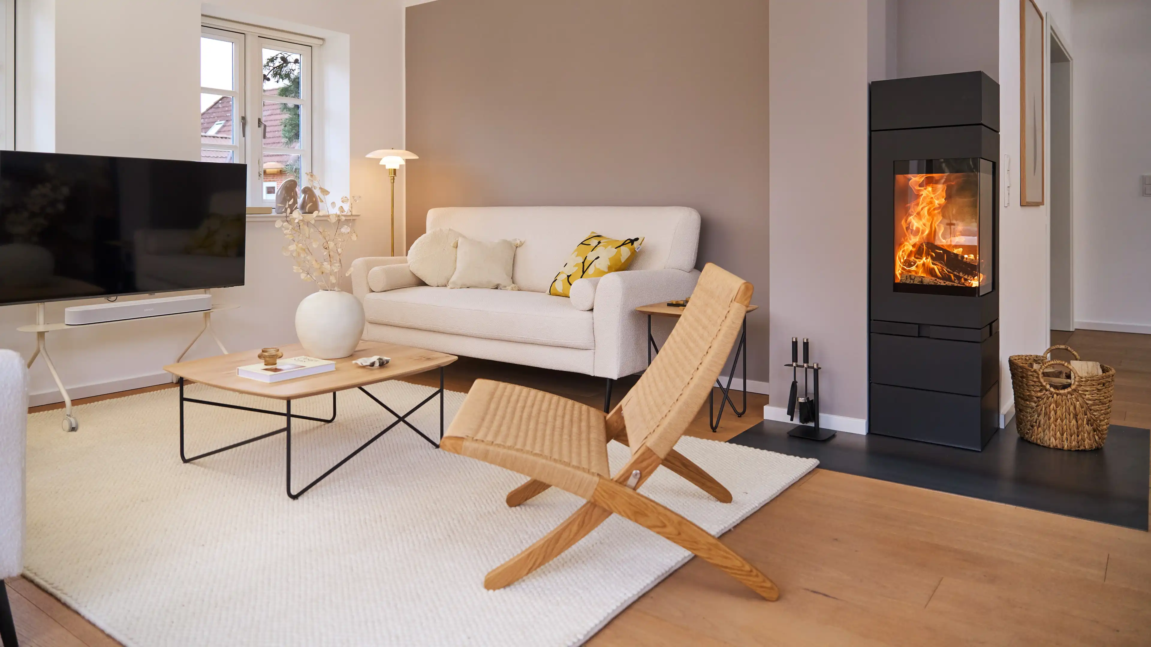 Das Wohnzimmer des Nordsee-Traumhauses mit Kamin und hellen Sitzmöbeln eingerichtet