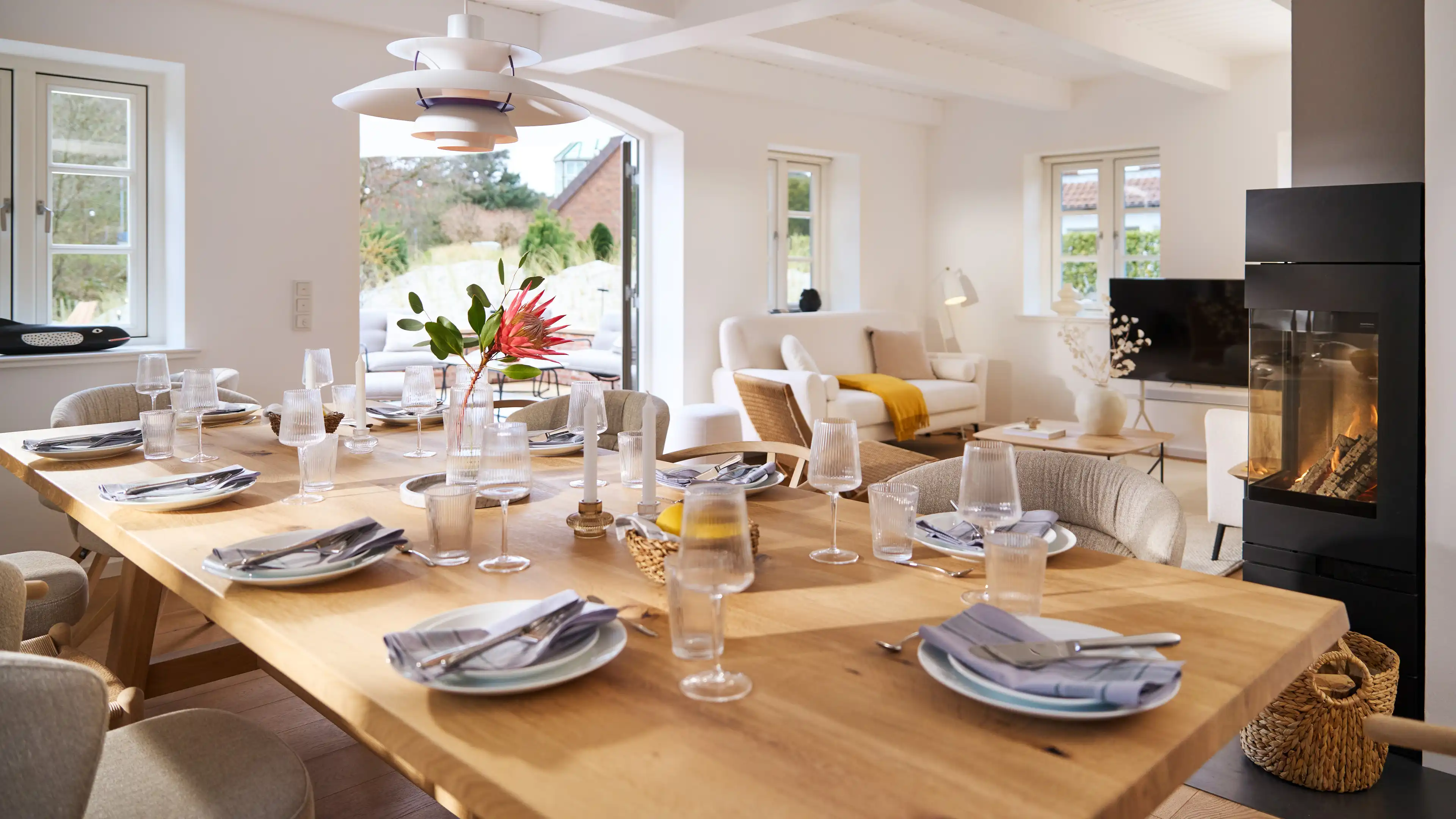 Offener Essbereich mit großem hellbraunen Esstisch für 12 Personen eingedeckt