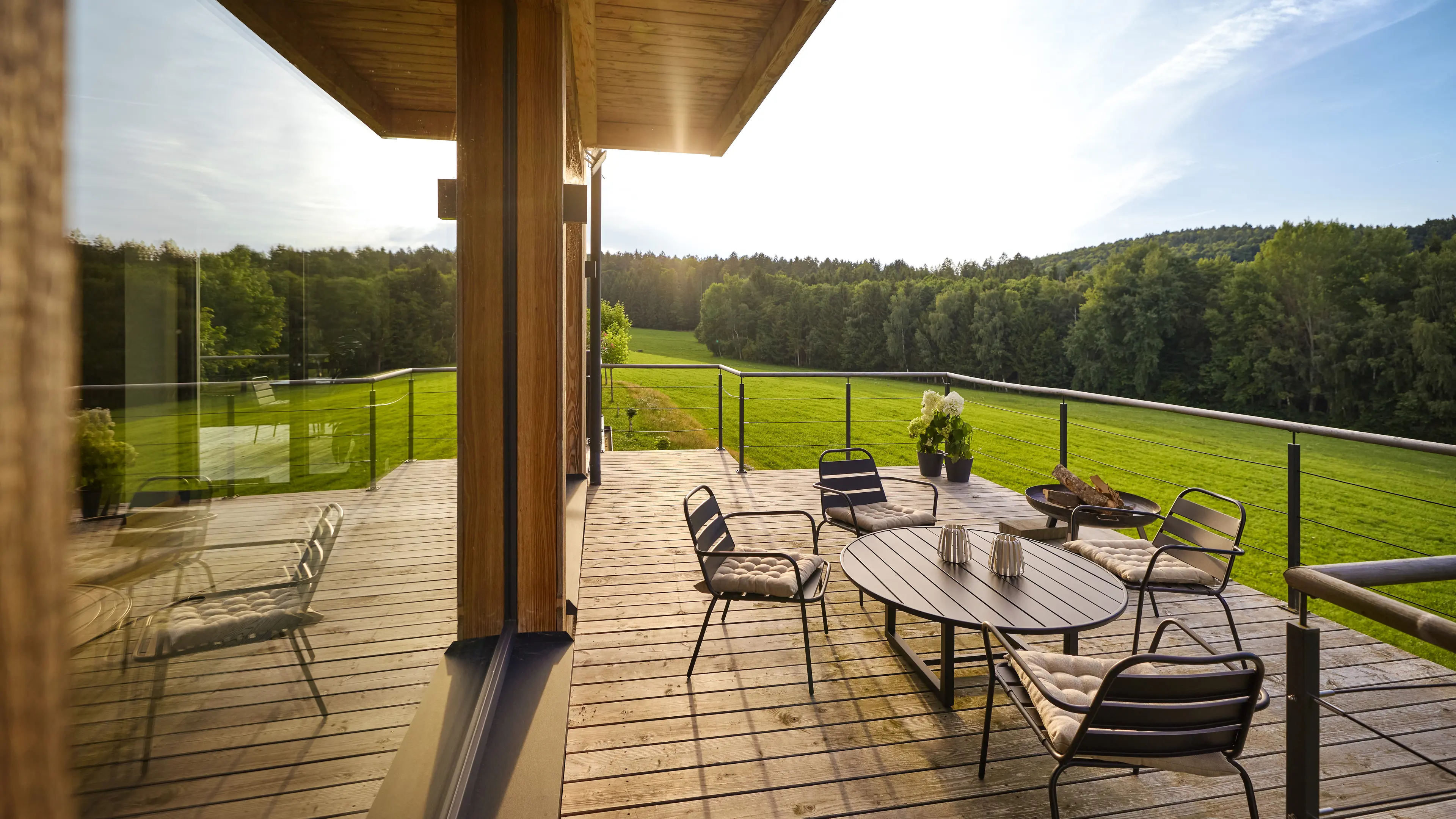 Ein Blick auf die Panorama-Terrasse mit Aussicht auf den Bayerischen Wald, Feuerschale und gemütlichen Sitzgelegenheiten