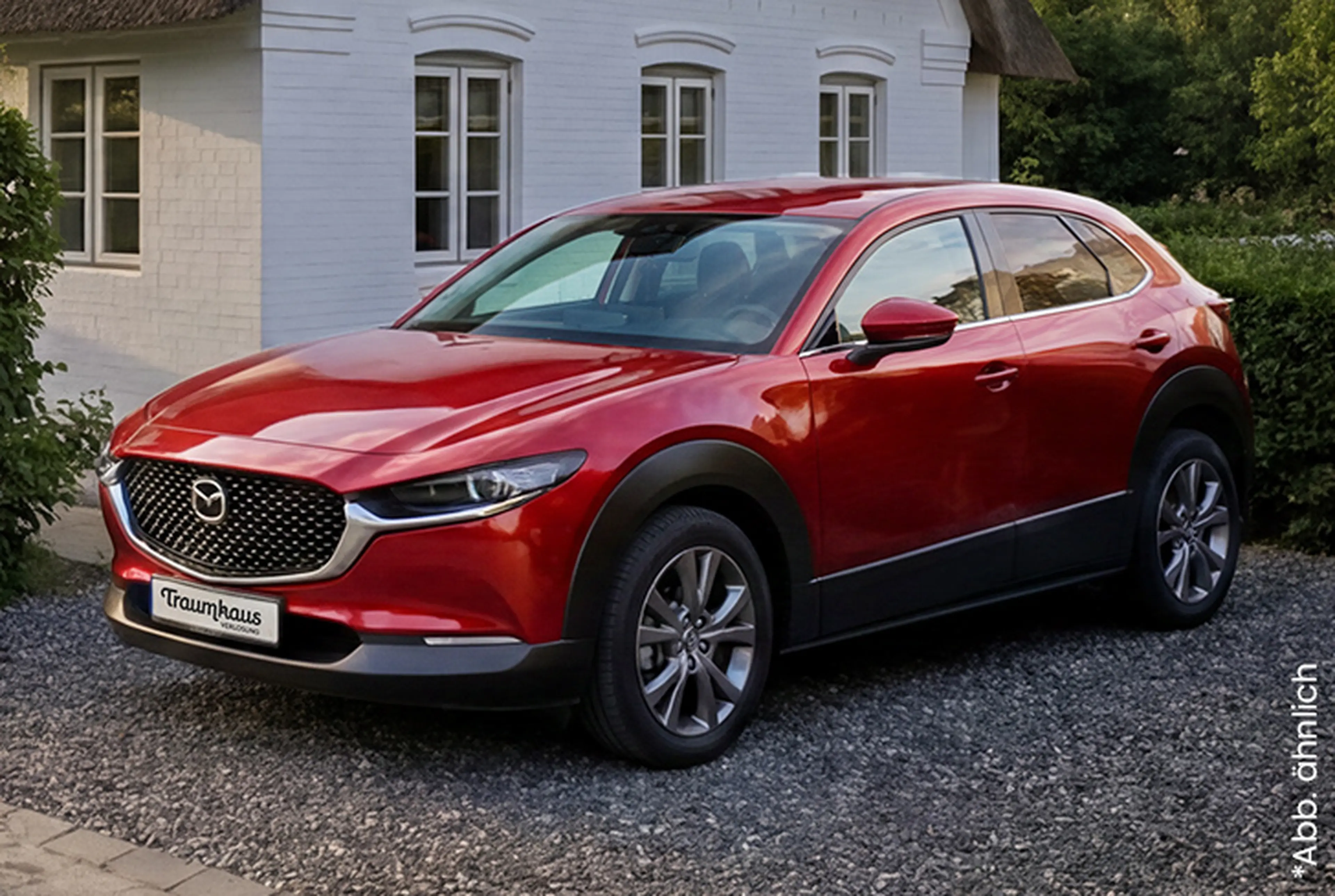 Seitliche Ansicht eines roten Mazdas CX-30 vor dem Traumhaus auf Amrum