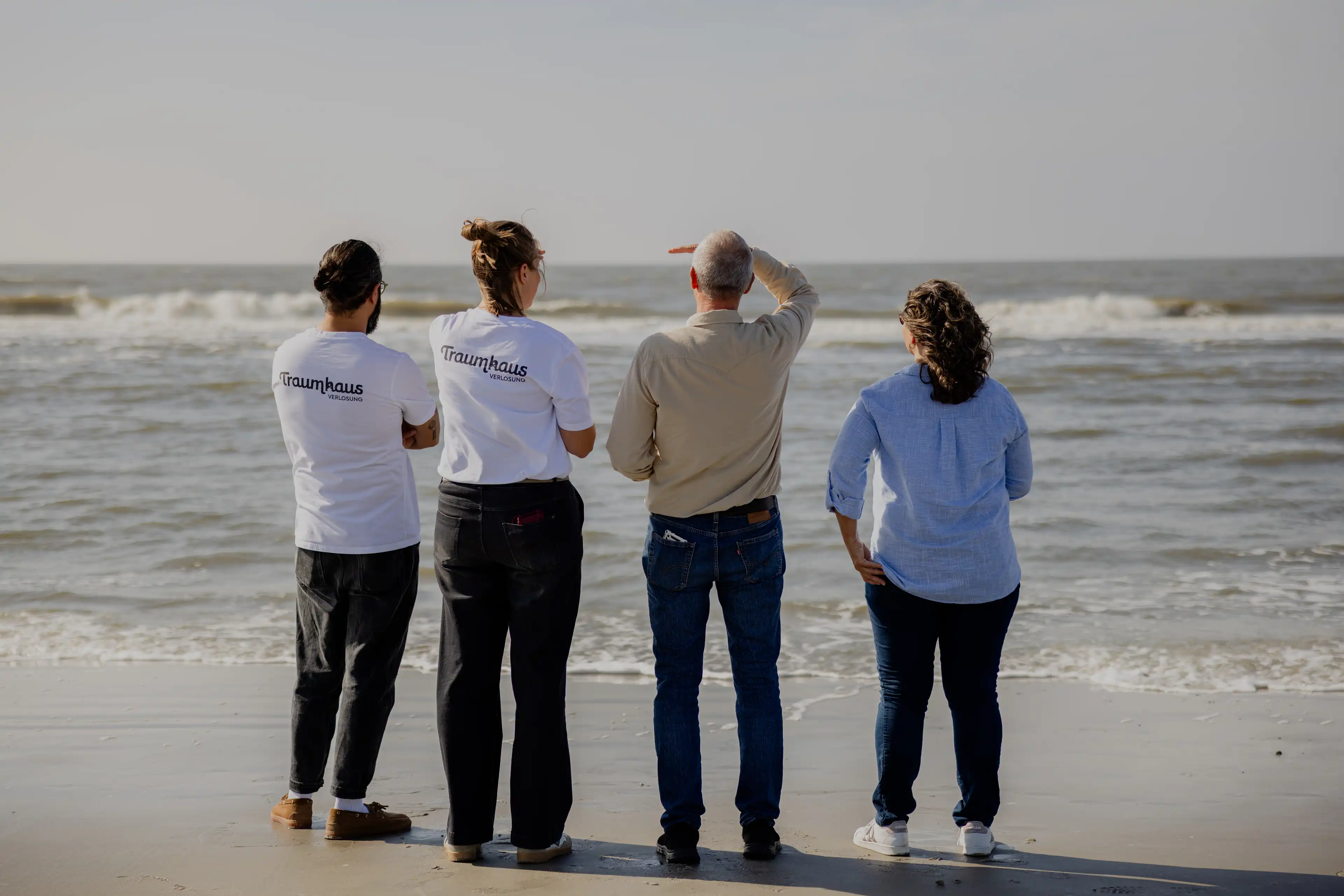 Thomas, Gewinner des Nordsee-Traumhauses, seine Frau und das Team der Traumhausverlosung schauen auf das Meer