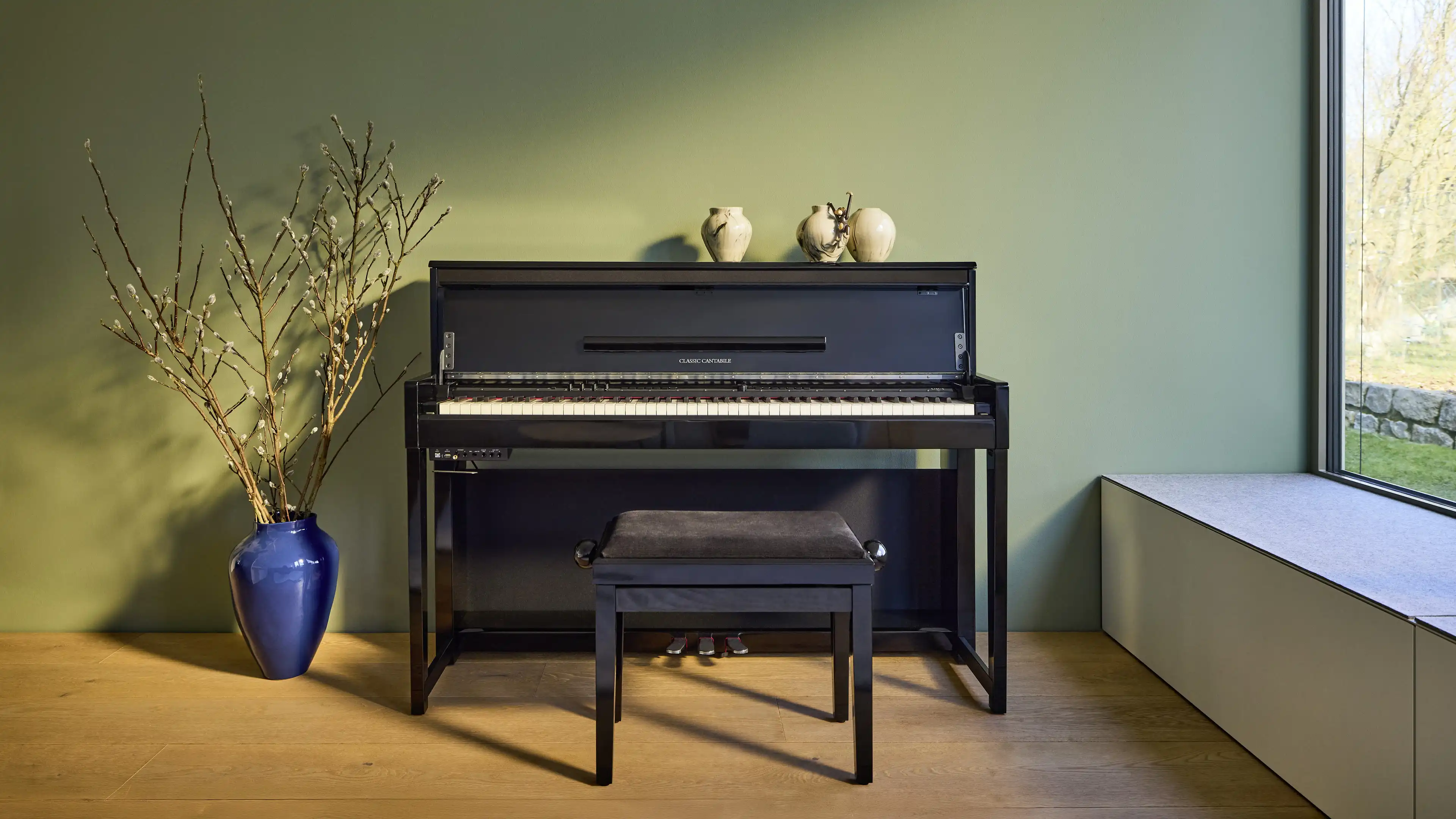 Schwarzes Piano vor dunkelgrüner Wand im Musikzimmer