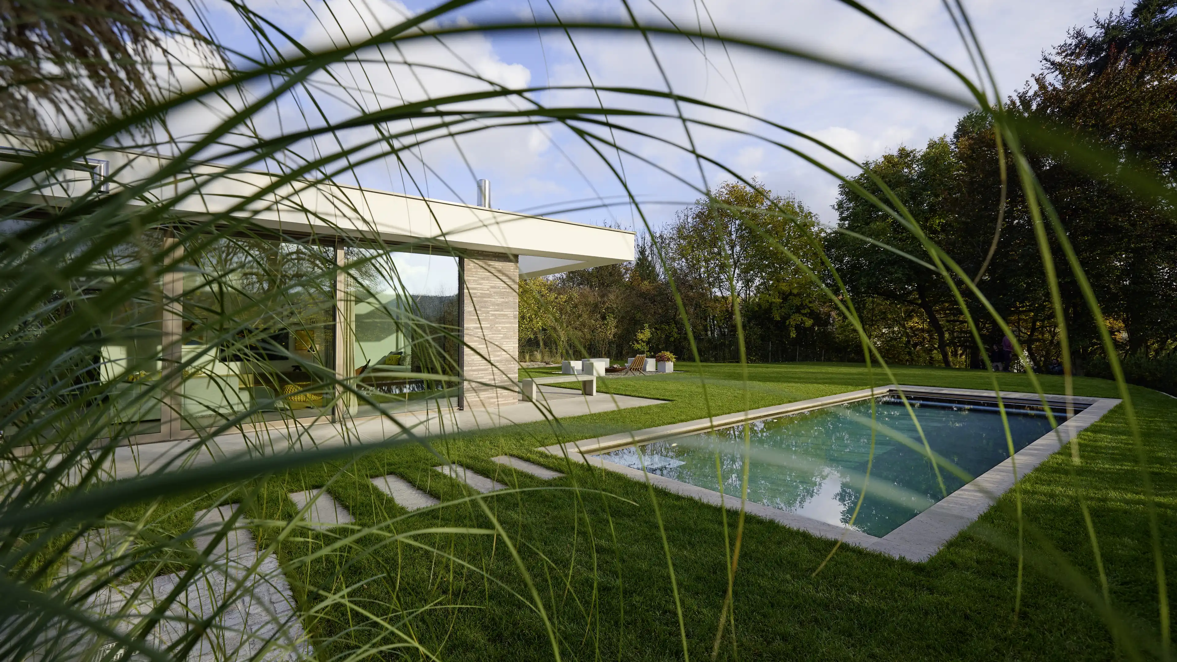 Blick auf den großen weitläufigen Garten mit langem Pool und Feuerstelle
