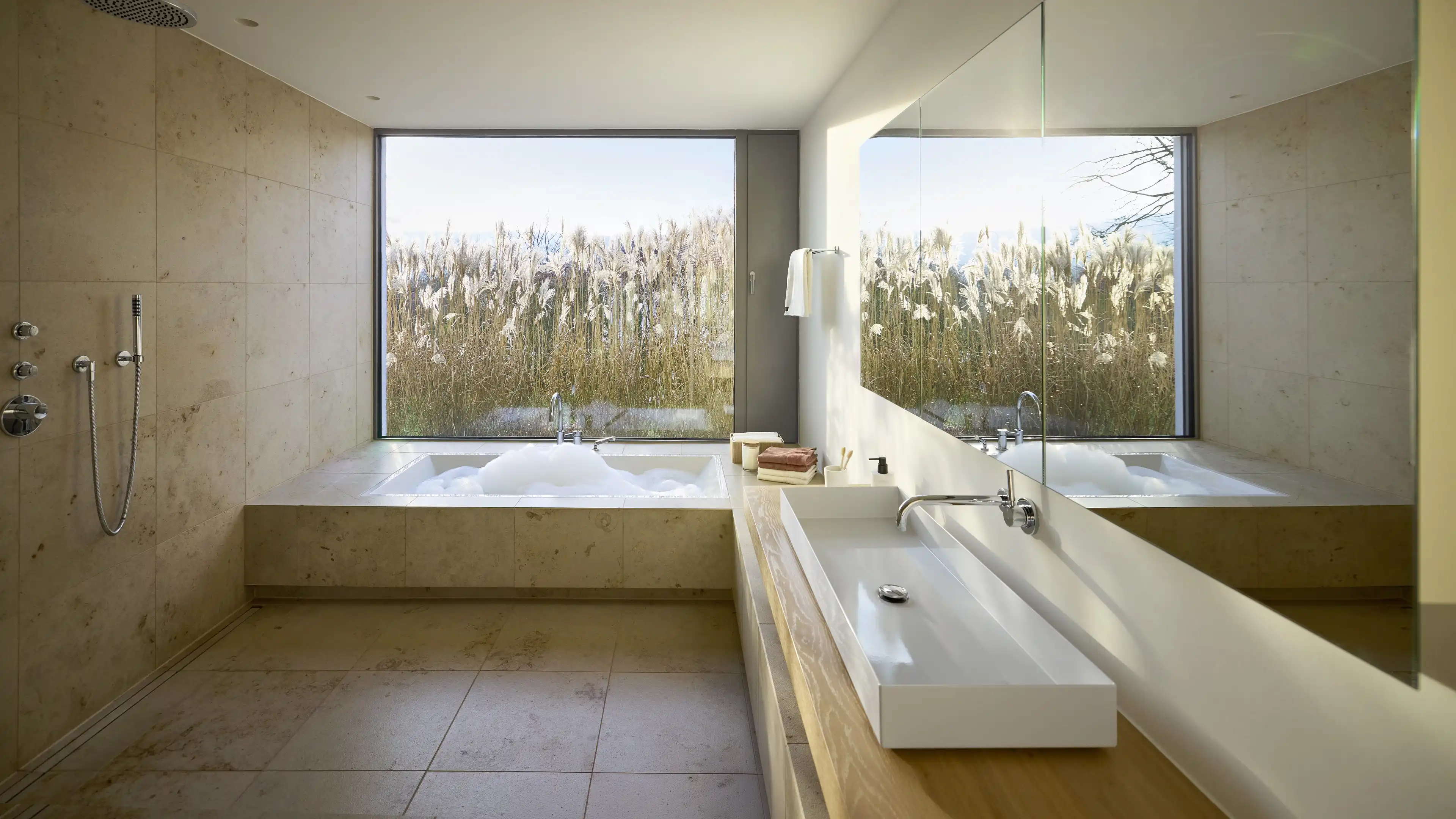 Zeitloses helles Bad mit freistehender Dusche und bodentiefer Badewanne und großem Panoramafenster
