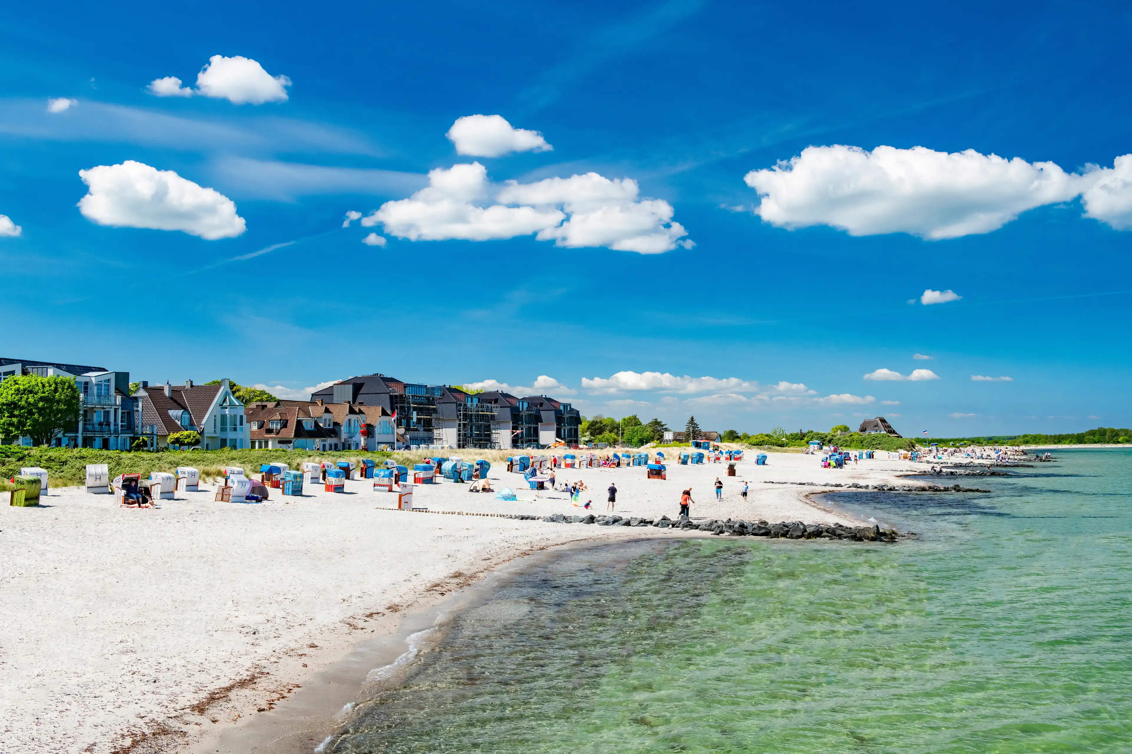Panoramablick auf den weißen Sandstrand und die Promenade von einem kleinen Ort an der Ostsee.